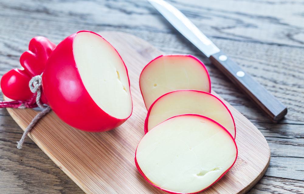 Sliced Provolone cheeses on the chopping board and a knife