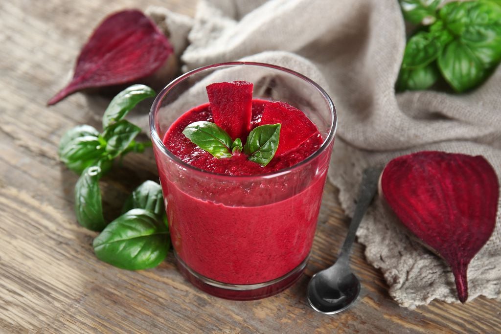 a cup of beets smoothie and a spoon on the table