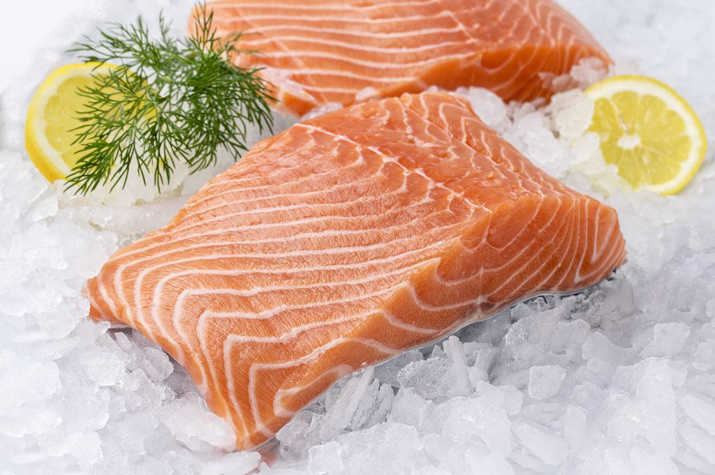 pieces of fresh salmon and sliced lemon on the ice
