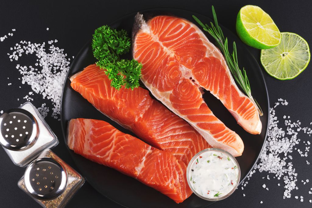 Fresh salmon and vegetables on the plate and slices of the lime