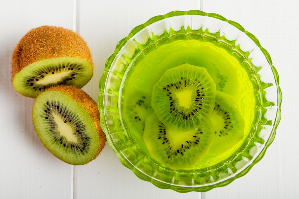 Slices of kiwi and a bowl of kiwi jello