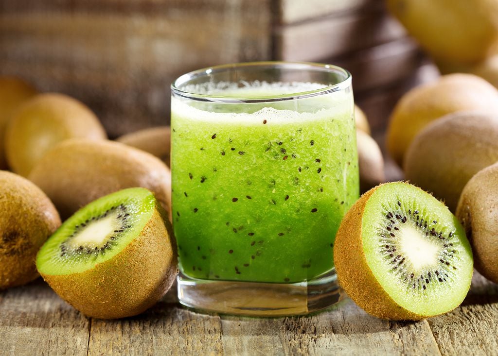 A cup of kiwi juice and kiwi on the table
