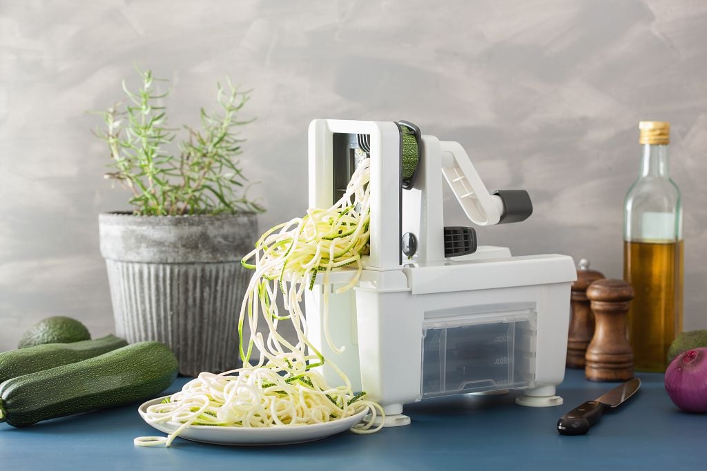 a zoodle maker, a knife, spice jars and fruits