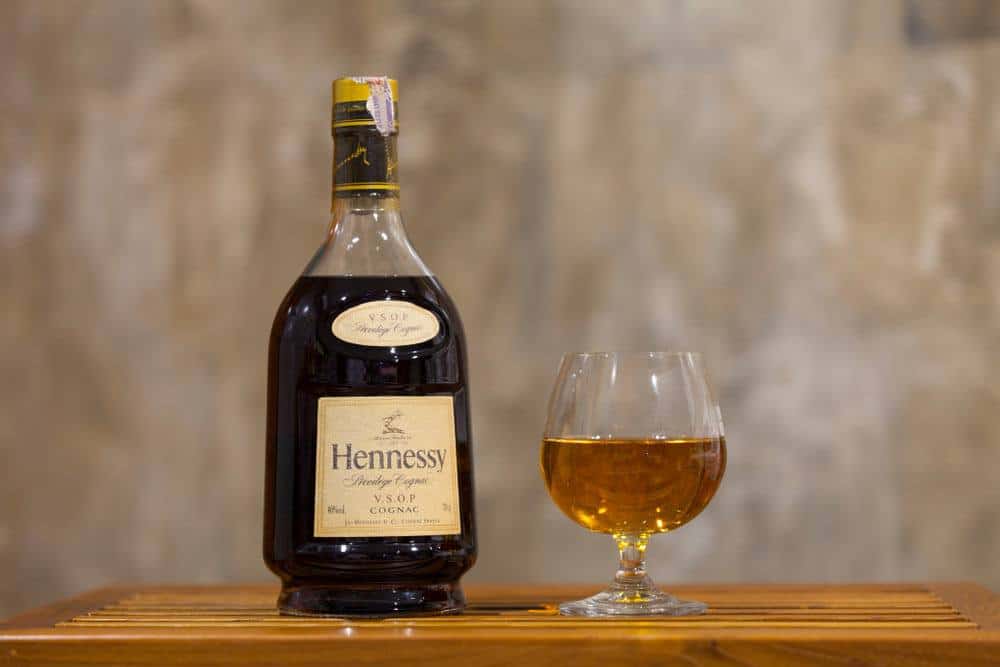 A bottle of Hennessy and a glass of Hennessy on the table