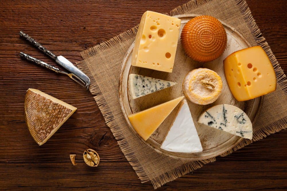 A plate of Cheese, a knife and a fork on the table