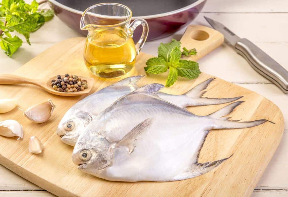 The Pompano, onion, a spoon of pepper and oil on the chopping board