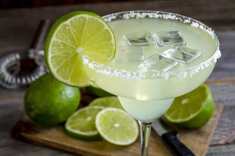 A glass of Patron Margarita and slices of lime