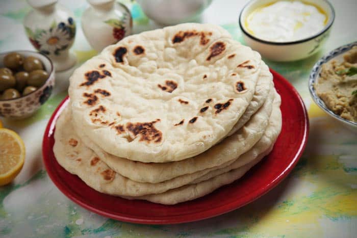 A plate of Pita Bread and slices of lemon on the table