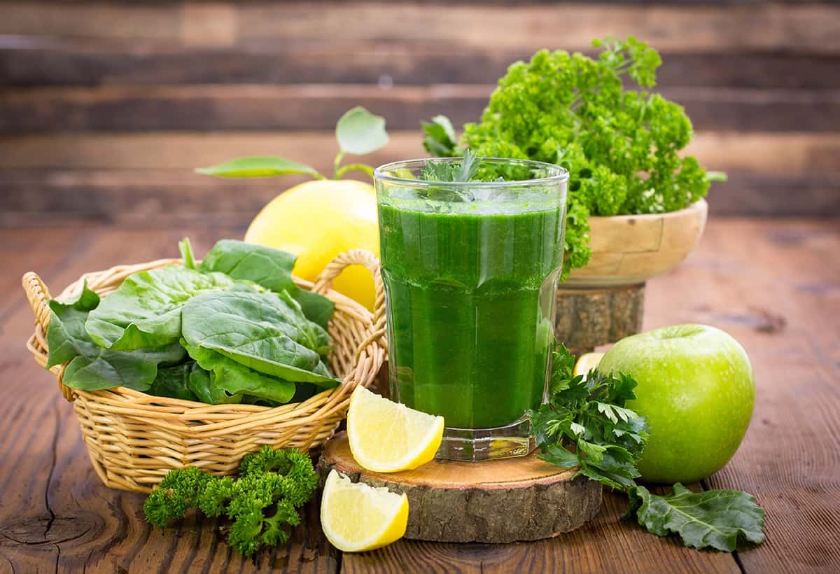 A cup of Romaine Lettuce-Apple Green Smoothie and fruits