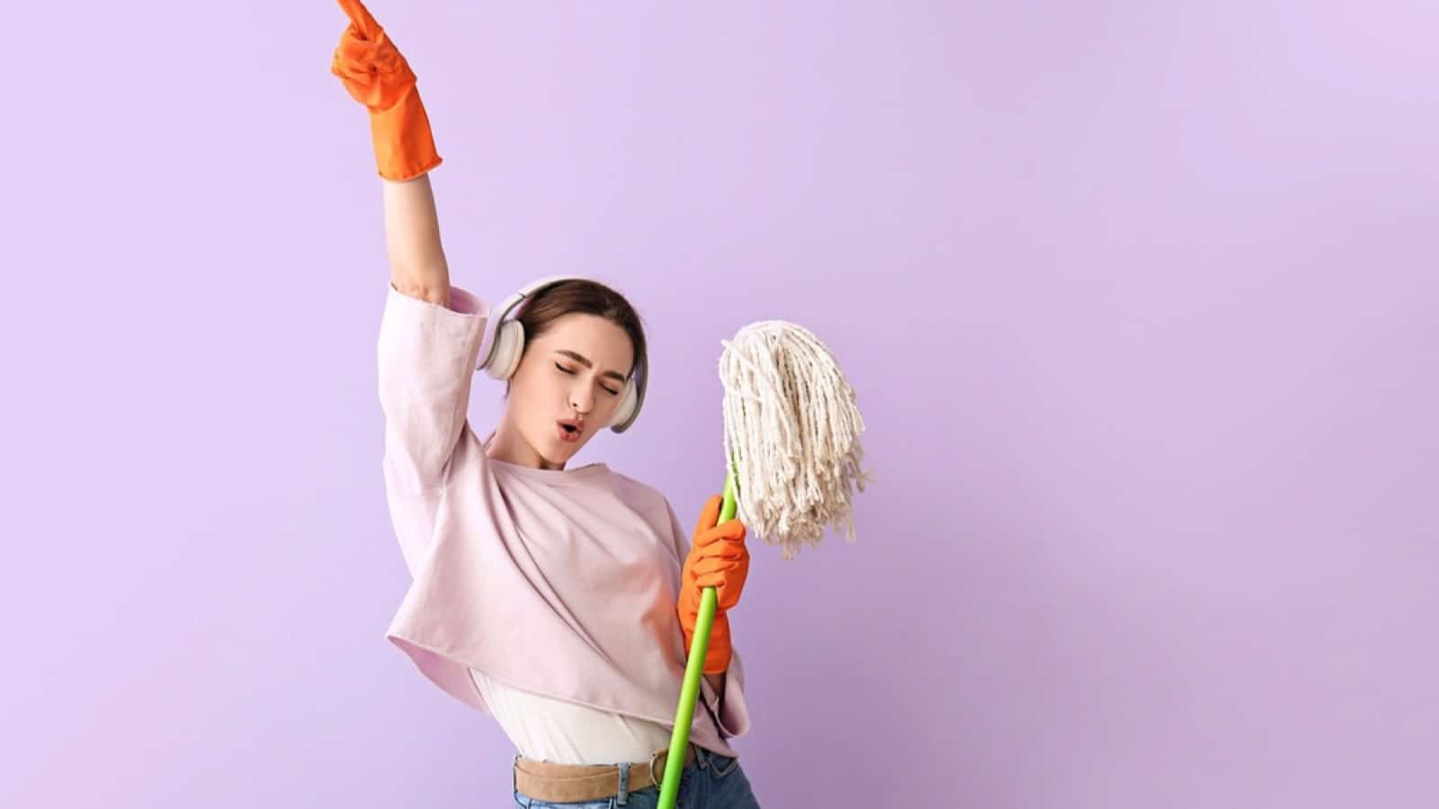 Young woman with floor mop listening to music